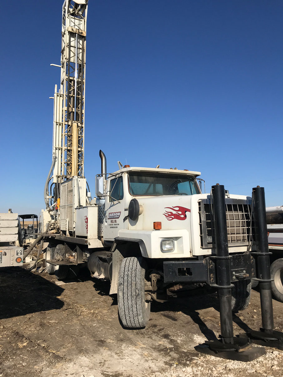Colored photo of white rotary drilling rig while drilling well 