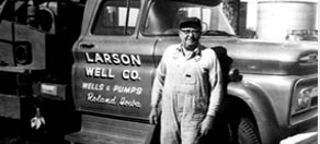 Black and white photo of Malcolm Larson against Larson Well Co. Cable tool drilling rig 