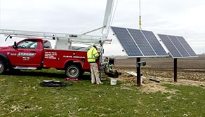 Photo of technician working on solar pump with red service truck in the background. 