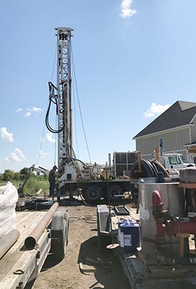 Colored photo of Riley Larson drilling a well at new home construction site 